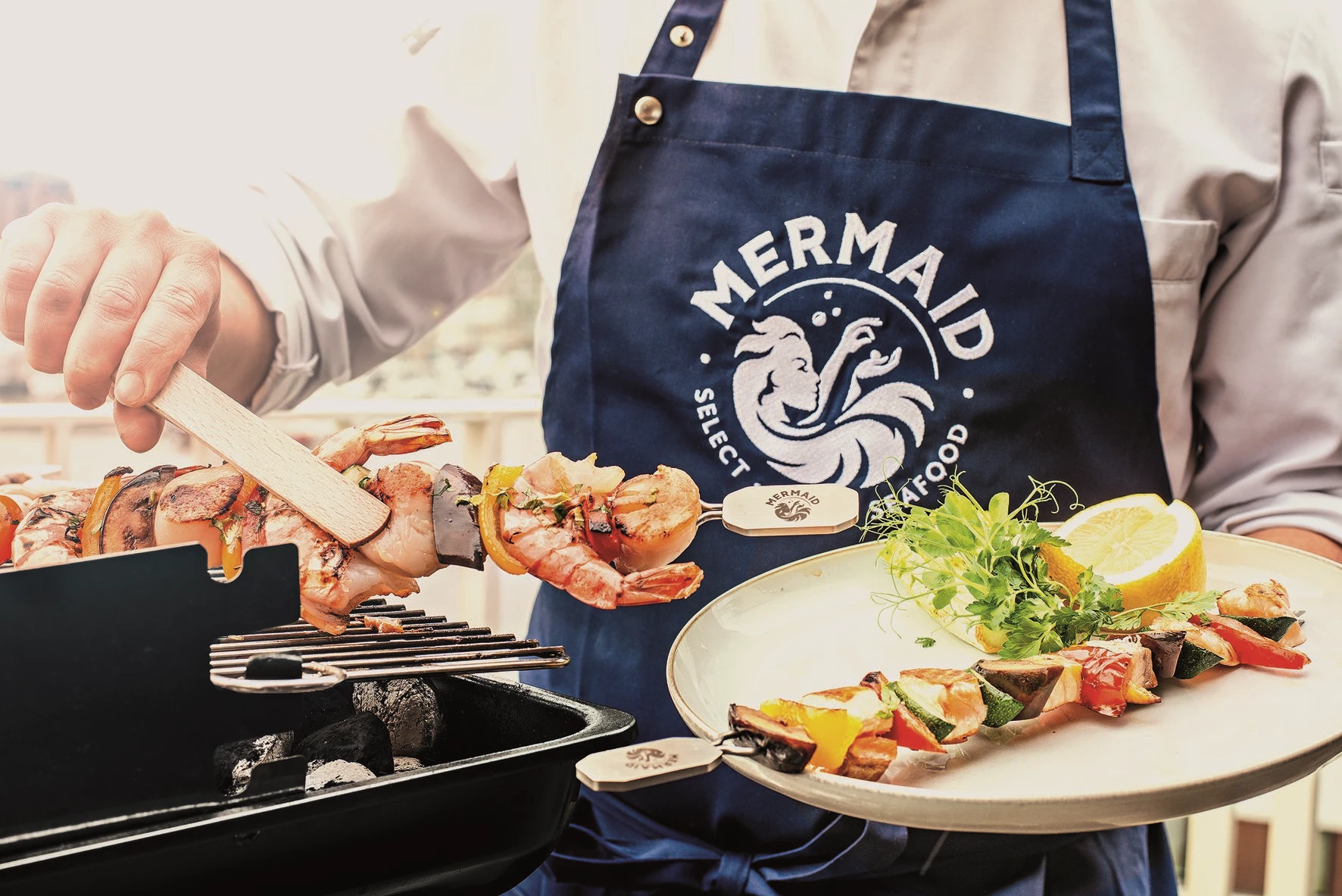 Vielfältige Produkte Mann in Mermaid-Schürze grillt Garnelenspieß
