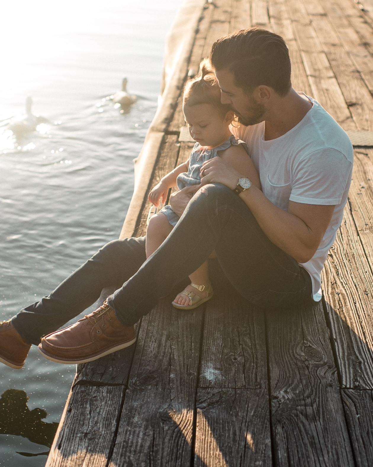 Vater sitzt mit Kind am See